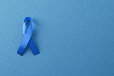 Blue awareness ribbon on color background, top view. Space for text