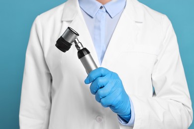 Photo of Dermatologist with dermatoscope on light blue background, closeup