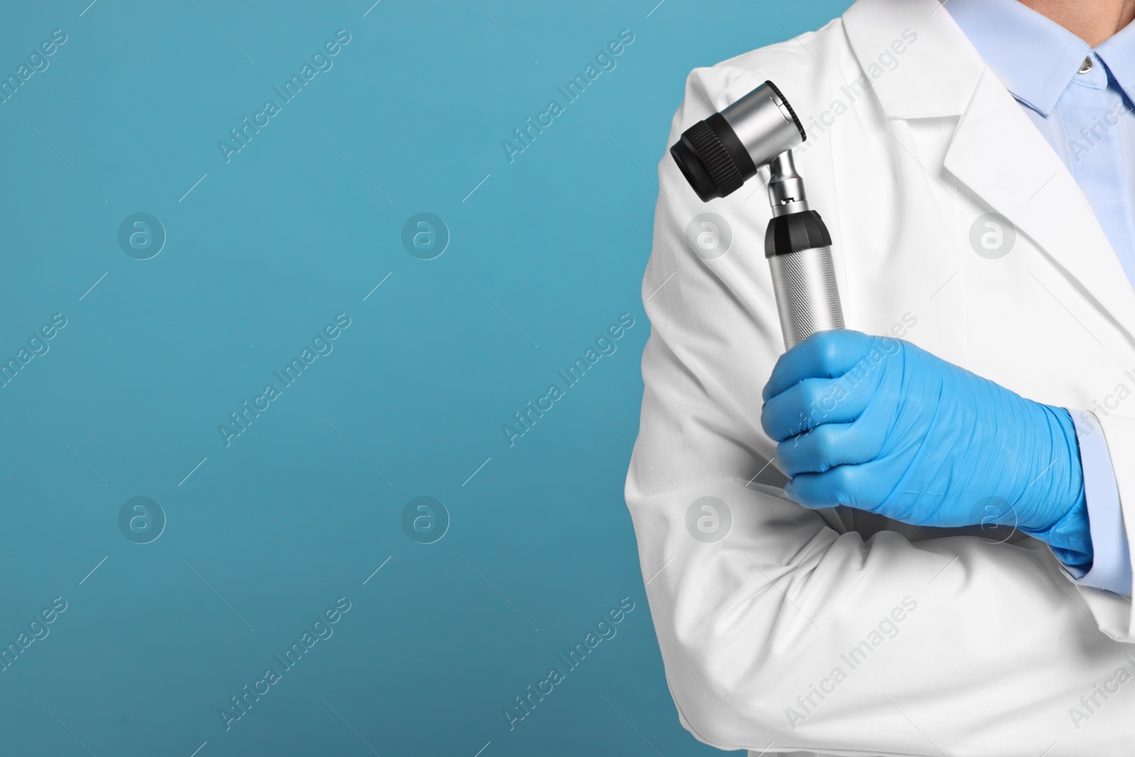 Photo of Dermatologist with dermatoscope on light blue background, closeup. Space for text
