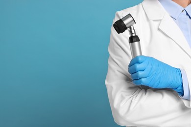 Dermatologist with dermatoscope on light blue background, closeup. Space for text