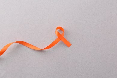 Orange awareness ribbon on gray background, top view. Space for text