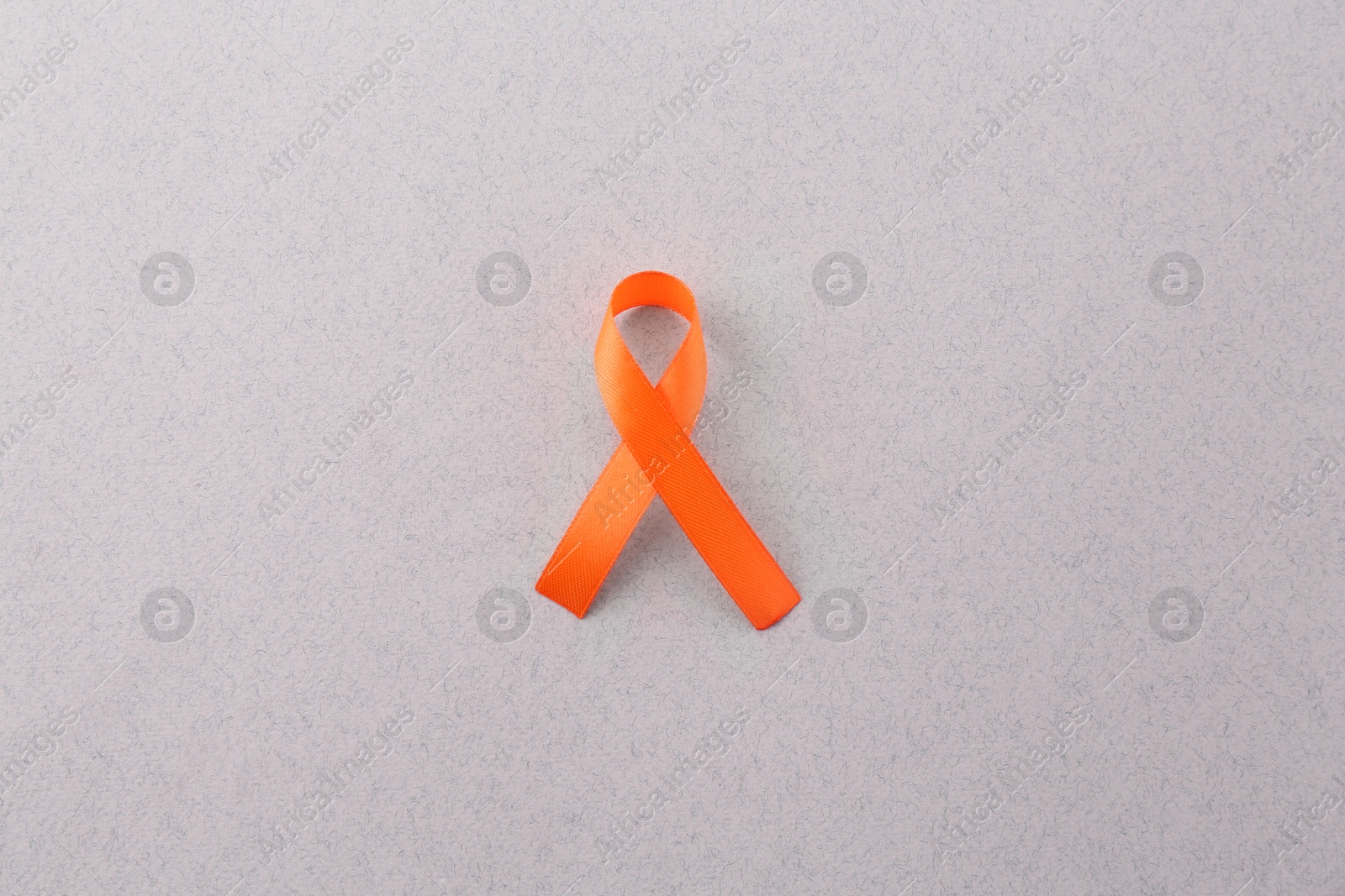 Photo of Orange awareness ribbon on gray background, top view