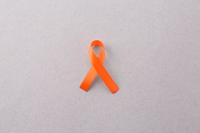 Photo of Orange awareness ribbon on gray background, top view