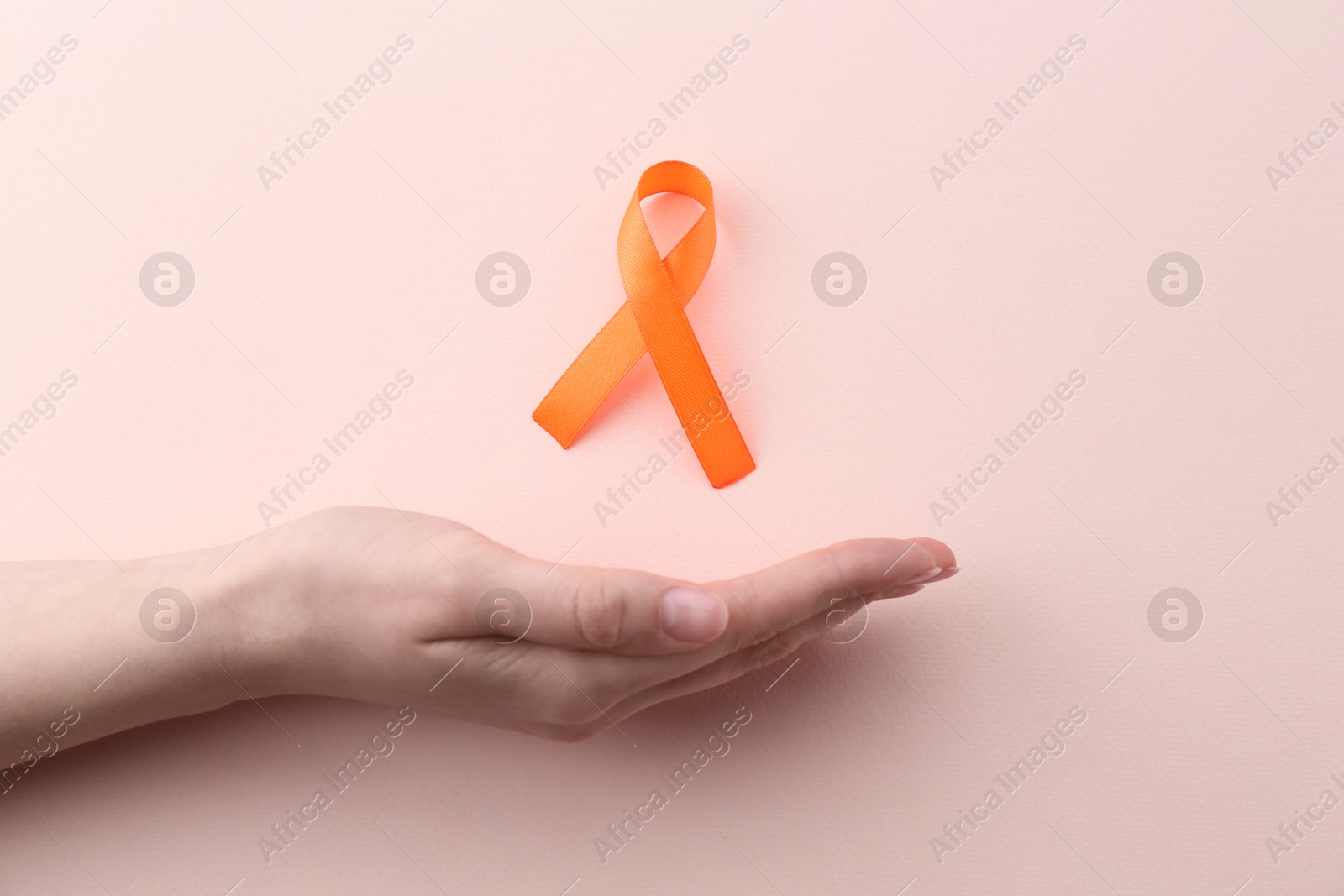 Photo of Woman with orange awareness ribbon on beige background, top view