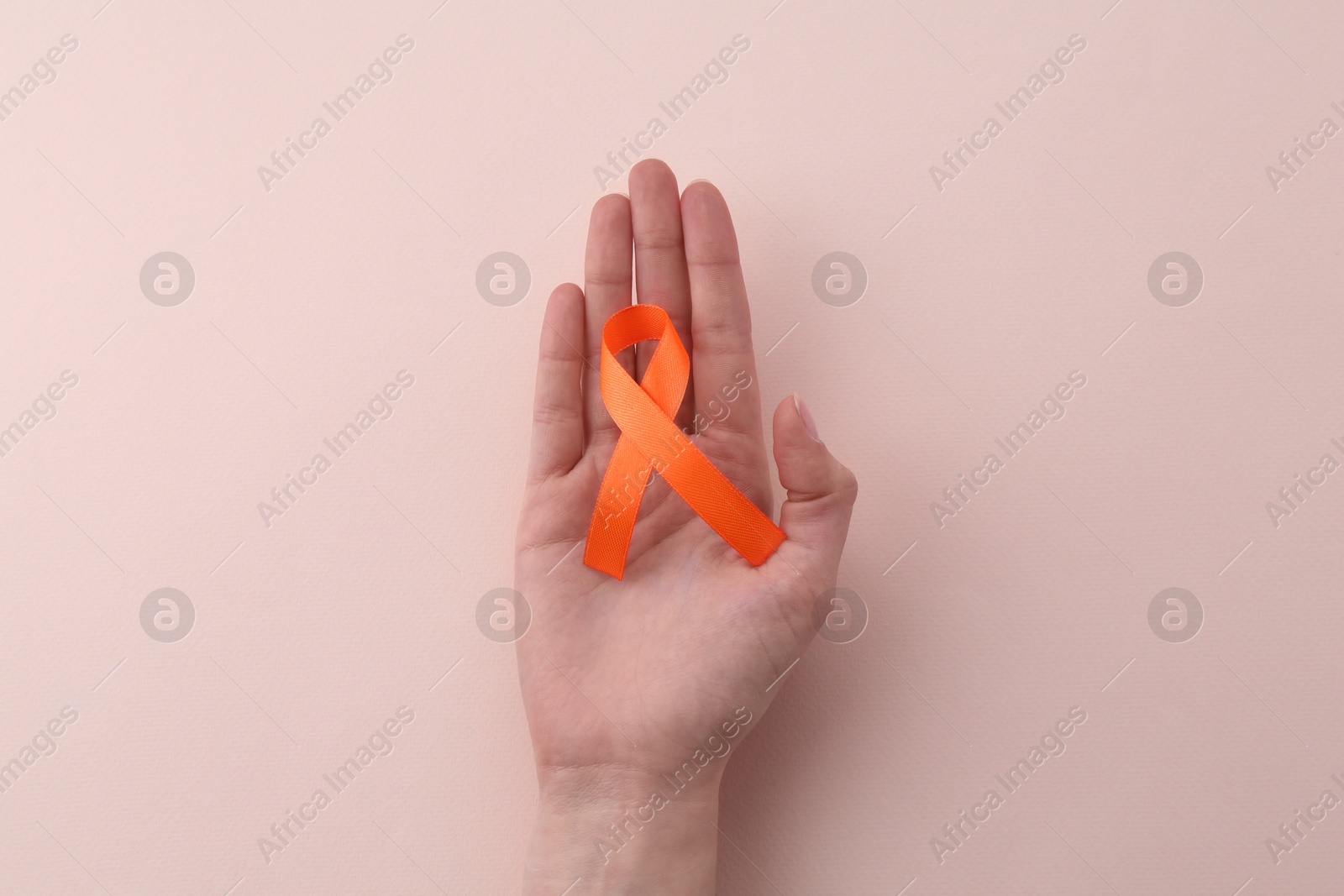 Photo of Woman with orange awareness ribbon on beige background, top view