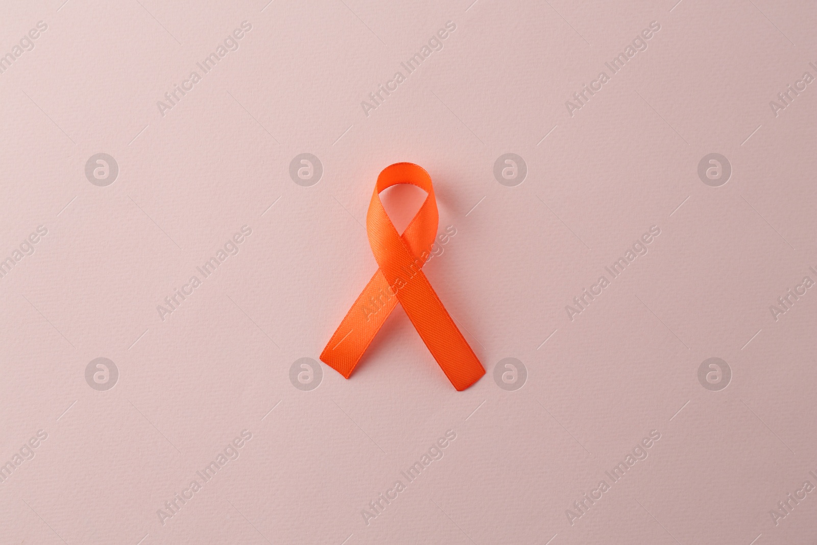 Photo of Orange awareness ribbon on beige background, top view