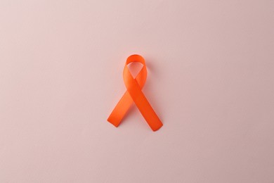 Orange awareness ribbon on beige background, top view