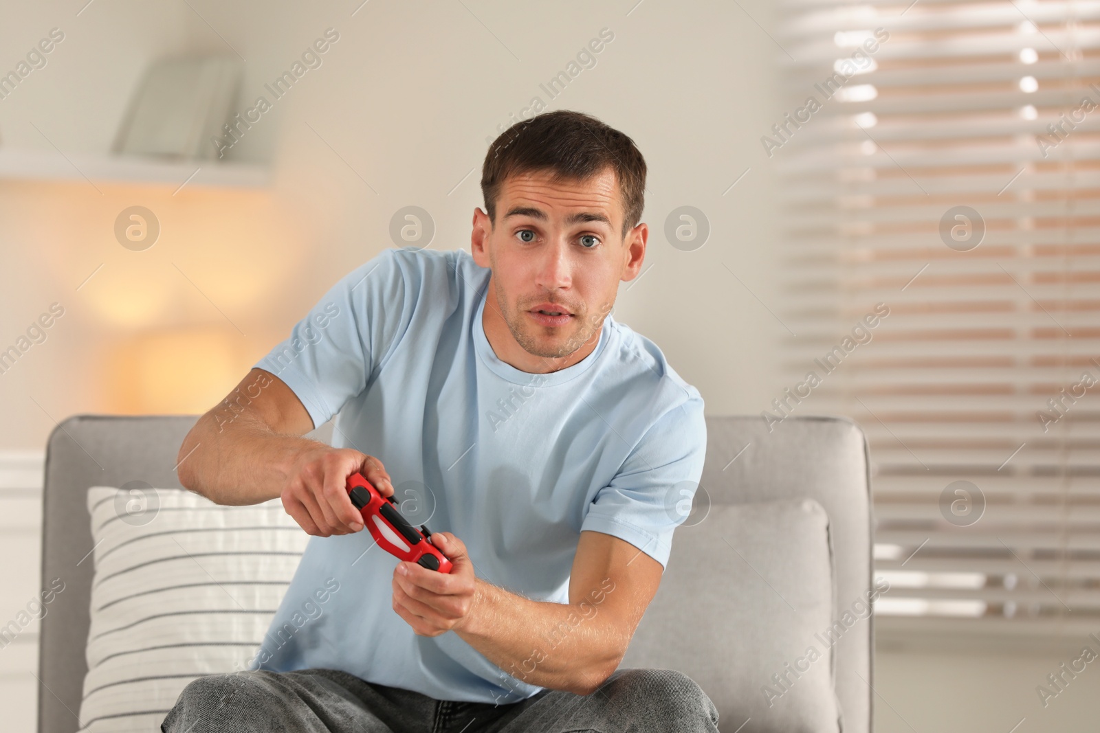 Photo of Man playing video games with joystick at home