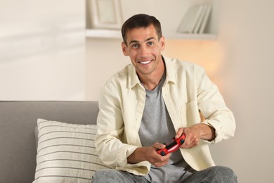 Photo of Happy man playing video games with joystick at home