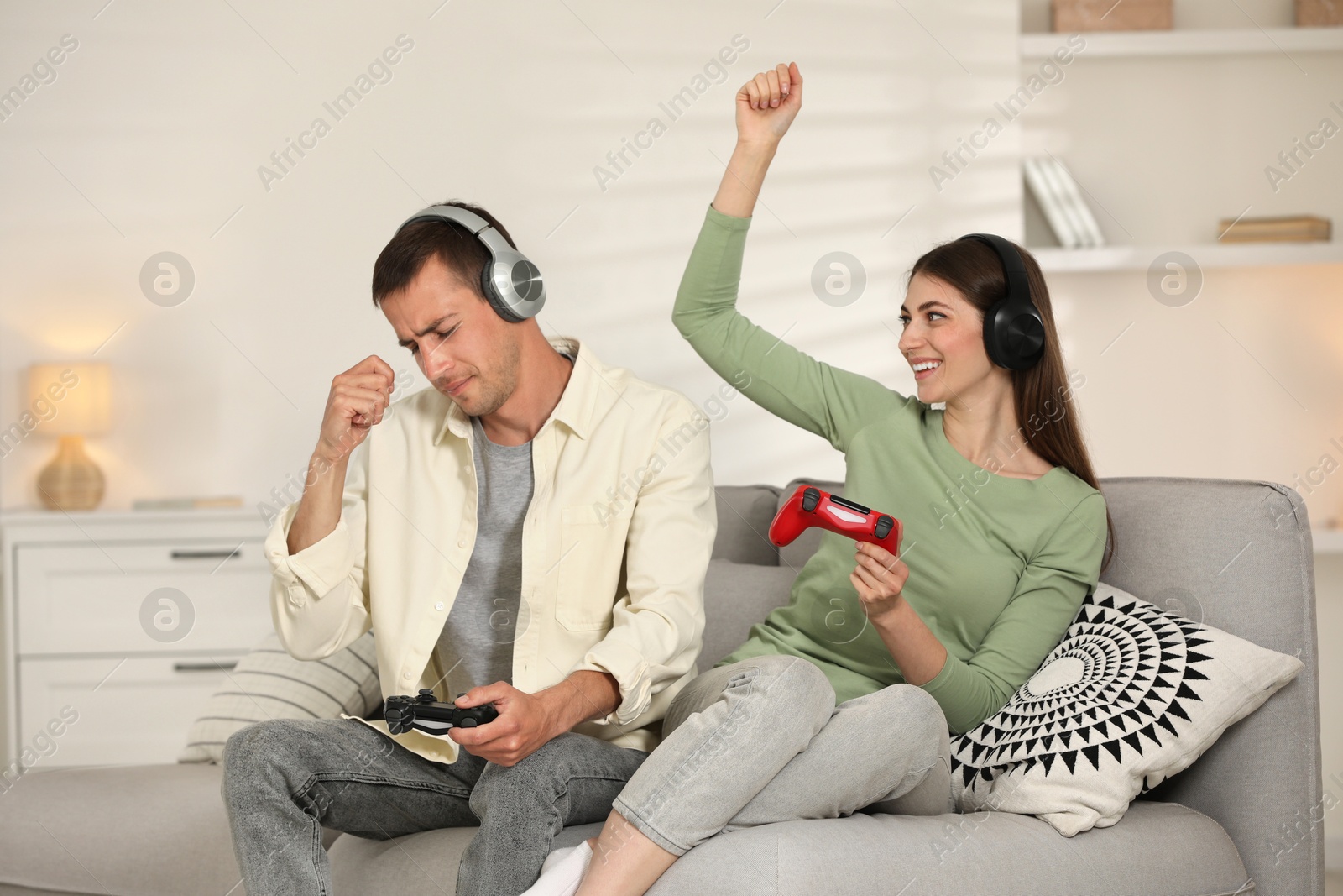 Photo of Couple playing video games with controllers at home