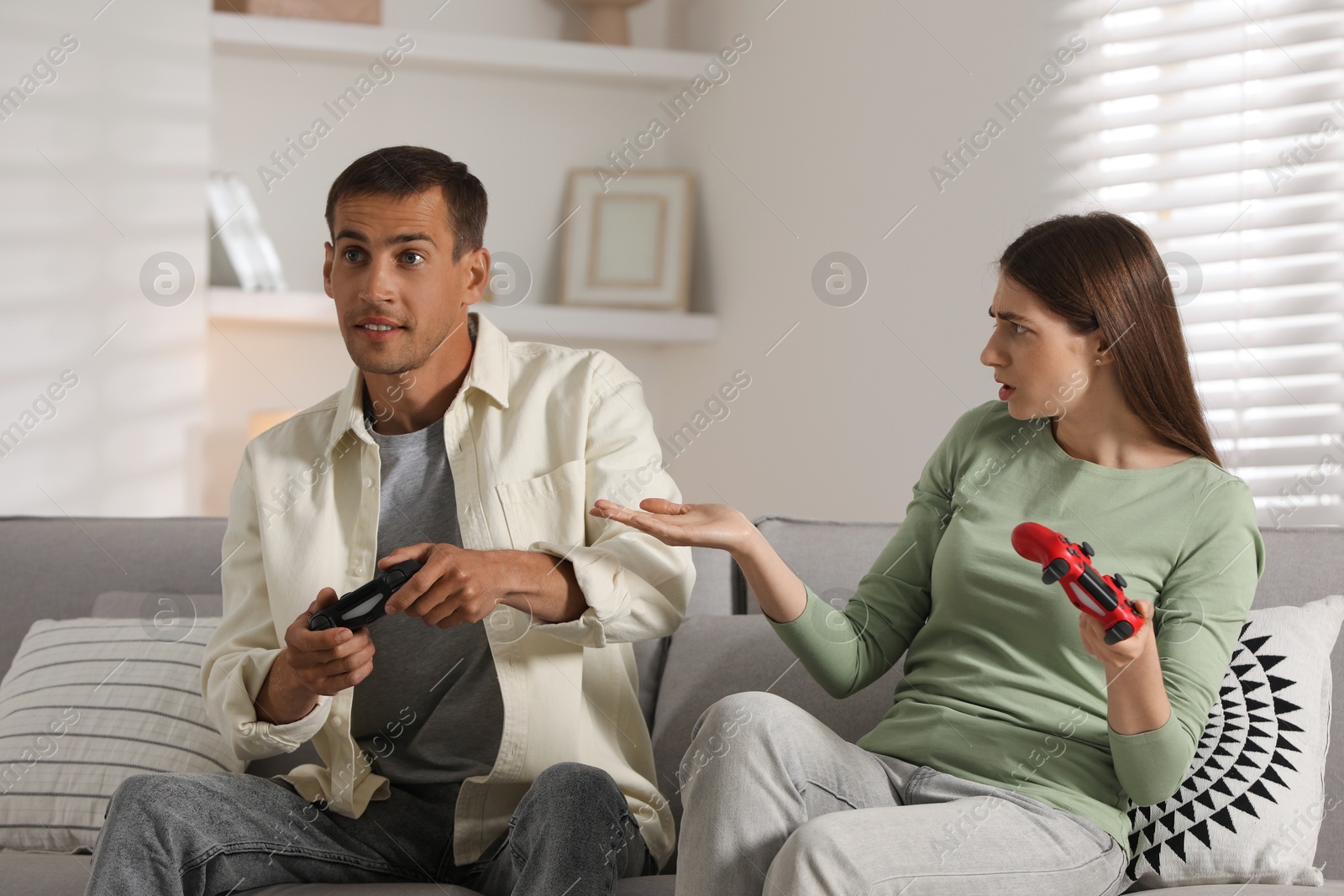 Photo of Couple playing video games with controllers at home