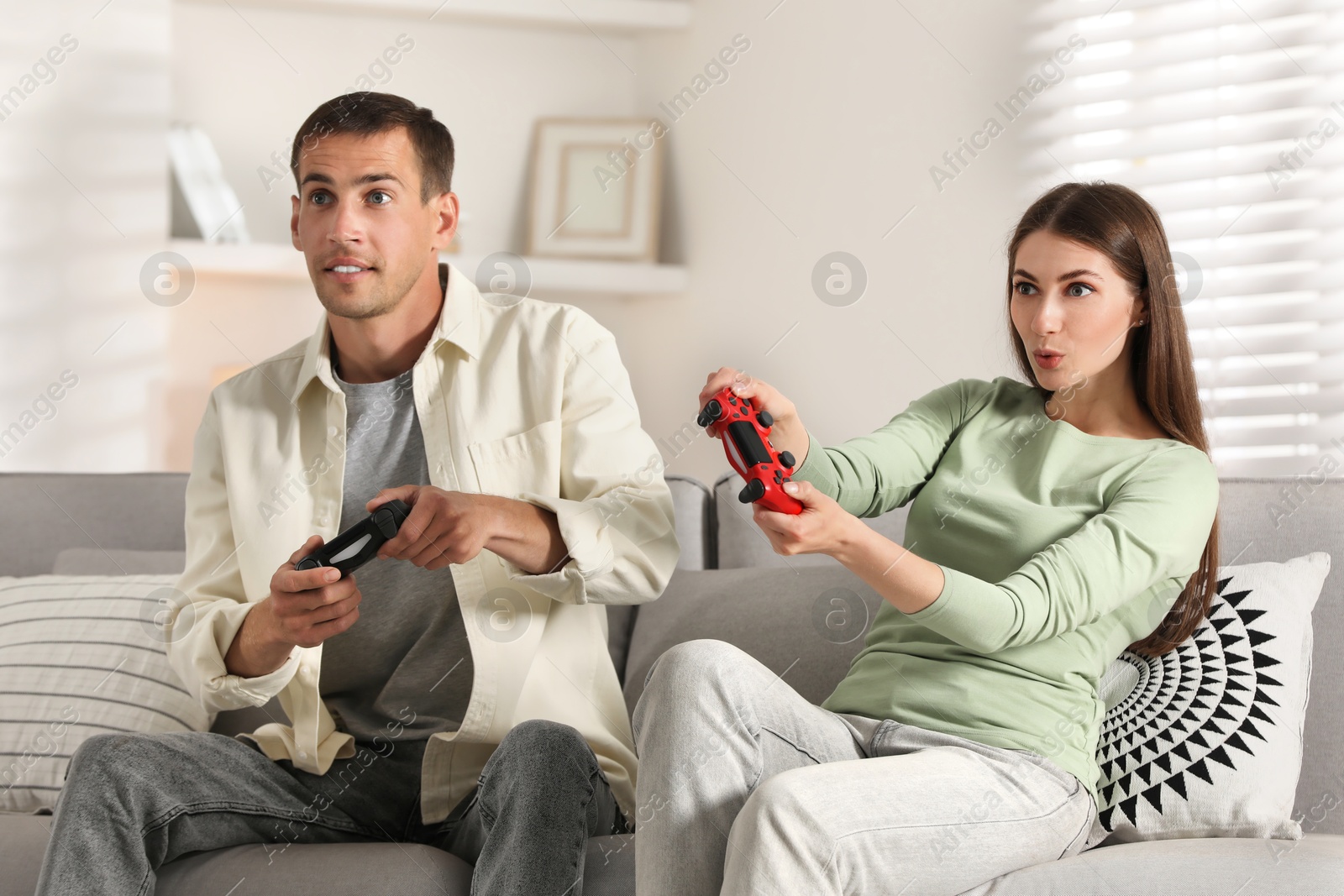 Photo of Couple playing video games with controllers at home