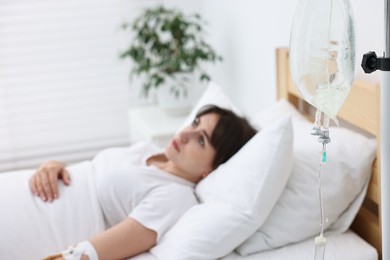 Photo of Young woman with intravenous drip in hospital bed, selective focus