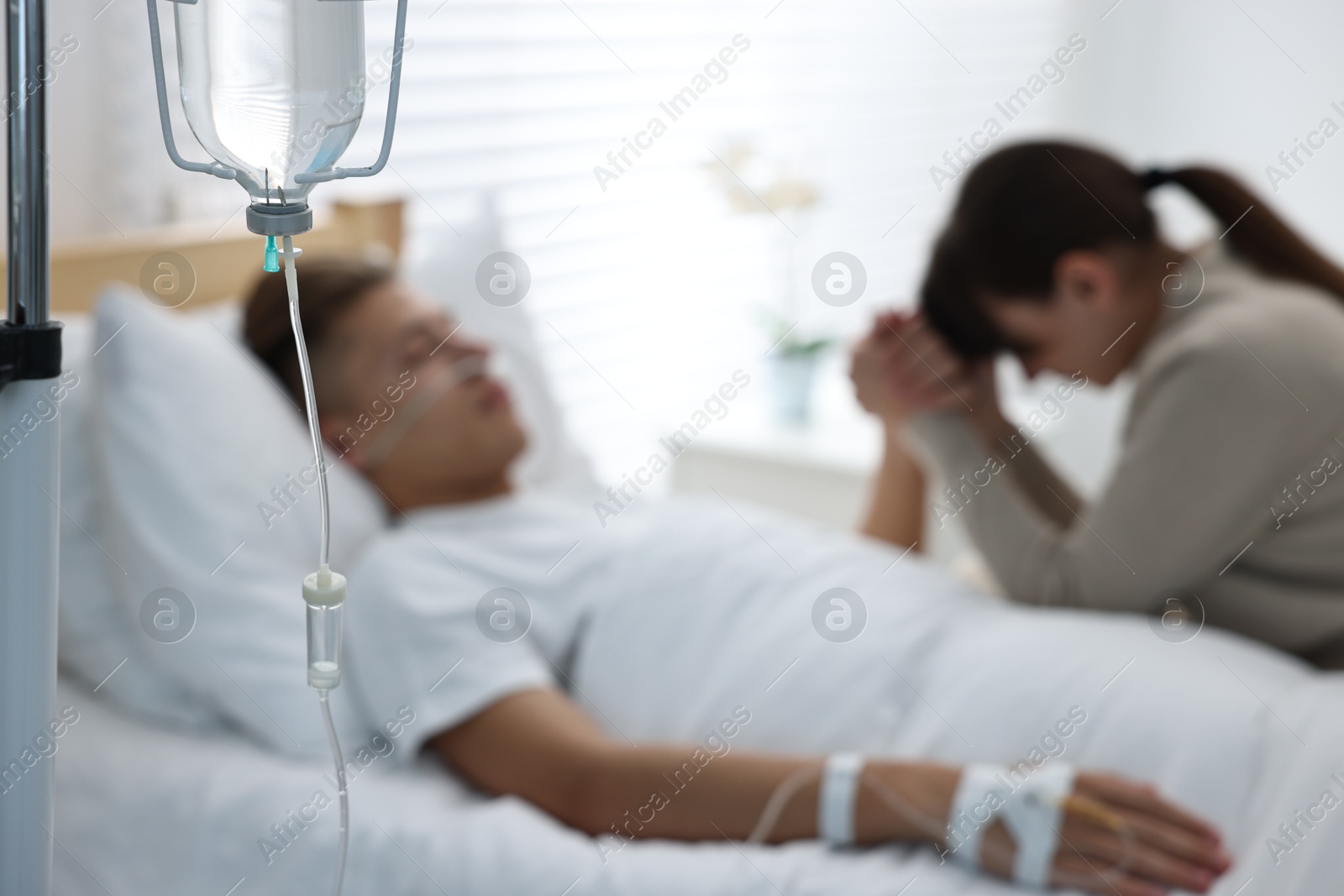 Photo of Coma patient. Sad young woman near her husband in hospital, selective focus