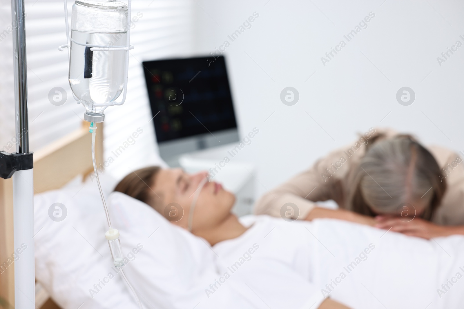 Photo of Coma patient. Sad mature woman near her unconscious son in hospital, selective focus