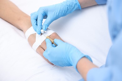 Nurse inserting IV into arm of patient in hospital, closeup
