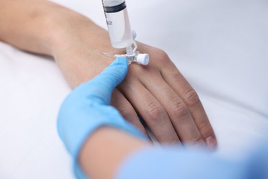 Nurse inserting IV into arm of patient in hospital, closeup