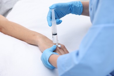 Photo of Nurse inserting IV into arm of patient in hospital, closeup