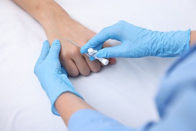 Photo of Nurse inputting catheter for IV drip in patient hand, closeup