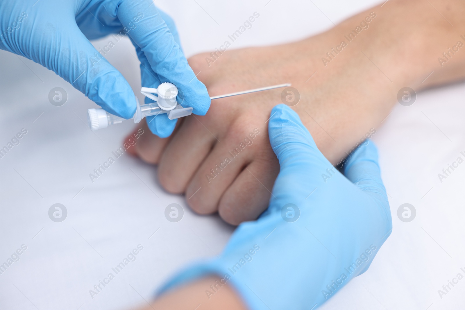 Photo of Nurse inputting catheter for IV drip in patient hand, closeup