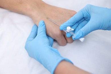 Photo of Nurse inputting catheter for IV drip in patient hand, closeup