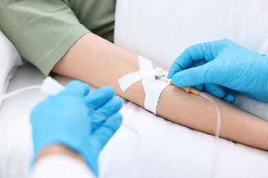 Nurse inserting IV into arm of patient in hospital, closeup