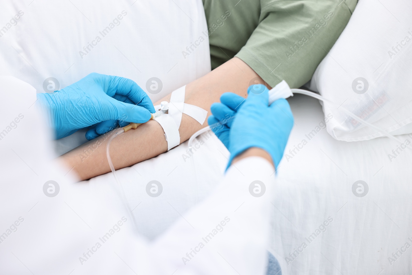 Photo of Nurse inserting IV into arm of patient in hospital, closeup