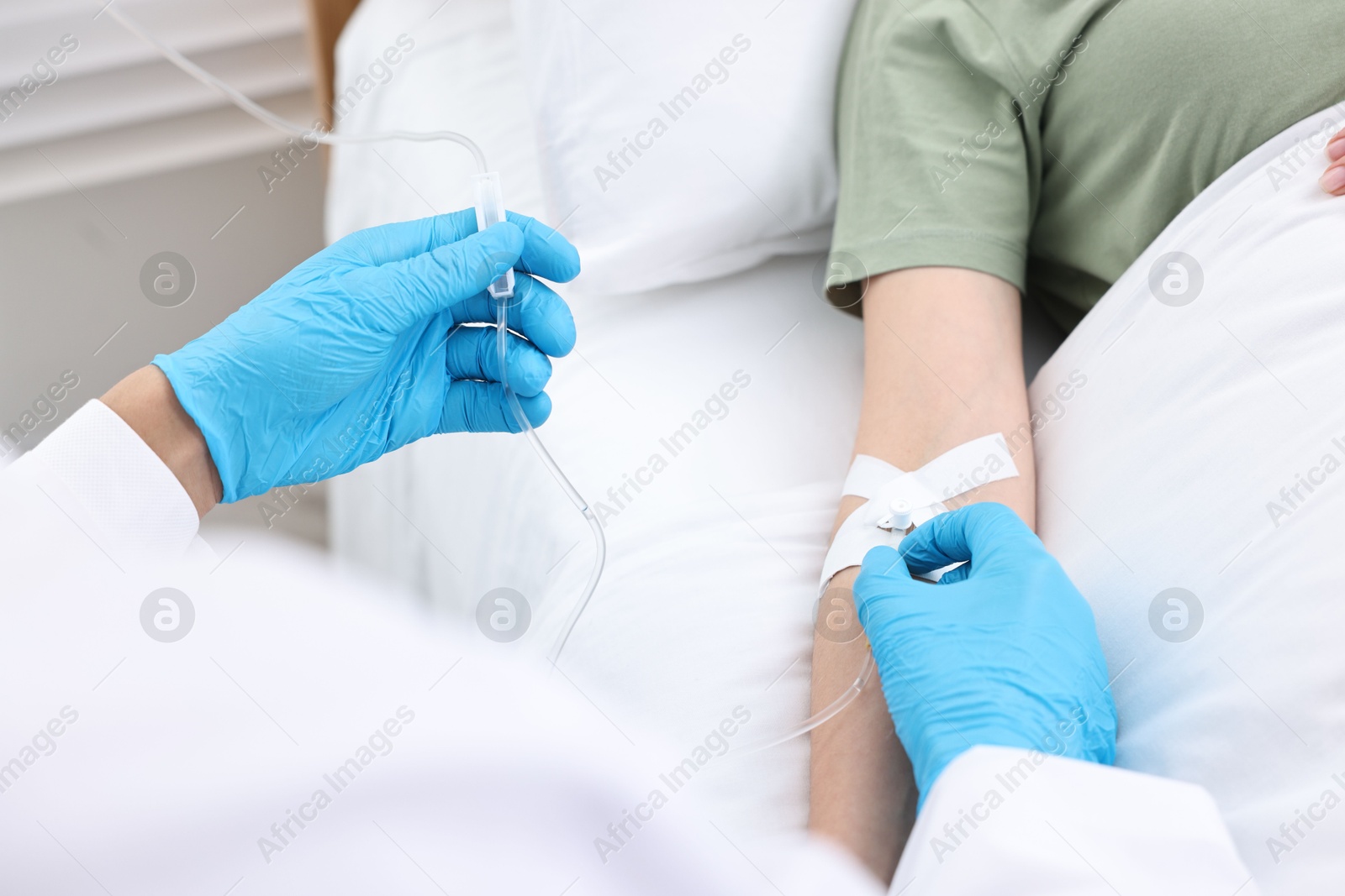 Photo of Nurse inserting IV into arm of patient in hospital, closeup