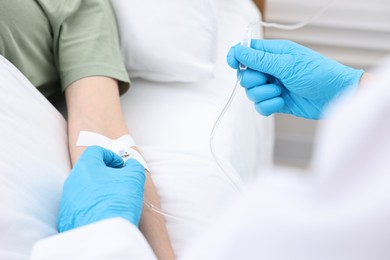 Nurse inserting IV into arm of patient in hospital, closeup