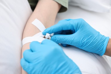 Photo of Nurse inserting IV into arm of patient in hospital, closeup