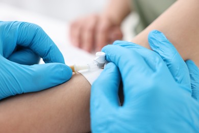 Nurse inserting IV into arm of patient in hospital, closeup