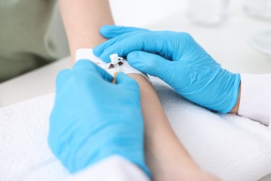 Nurse inserting IV into arm of patient in hospital, closeup