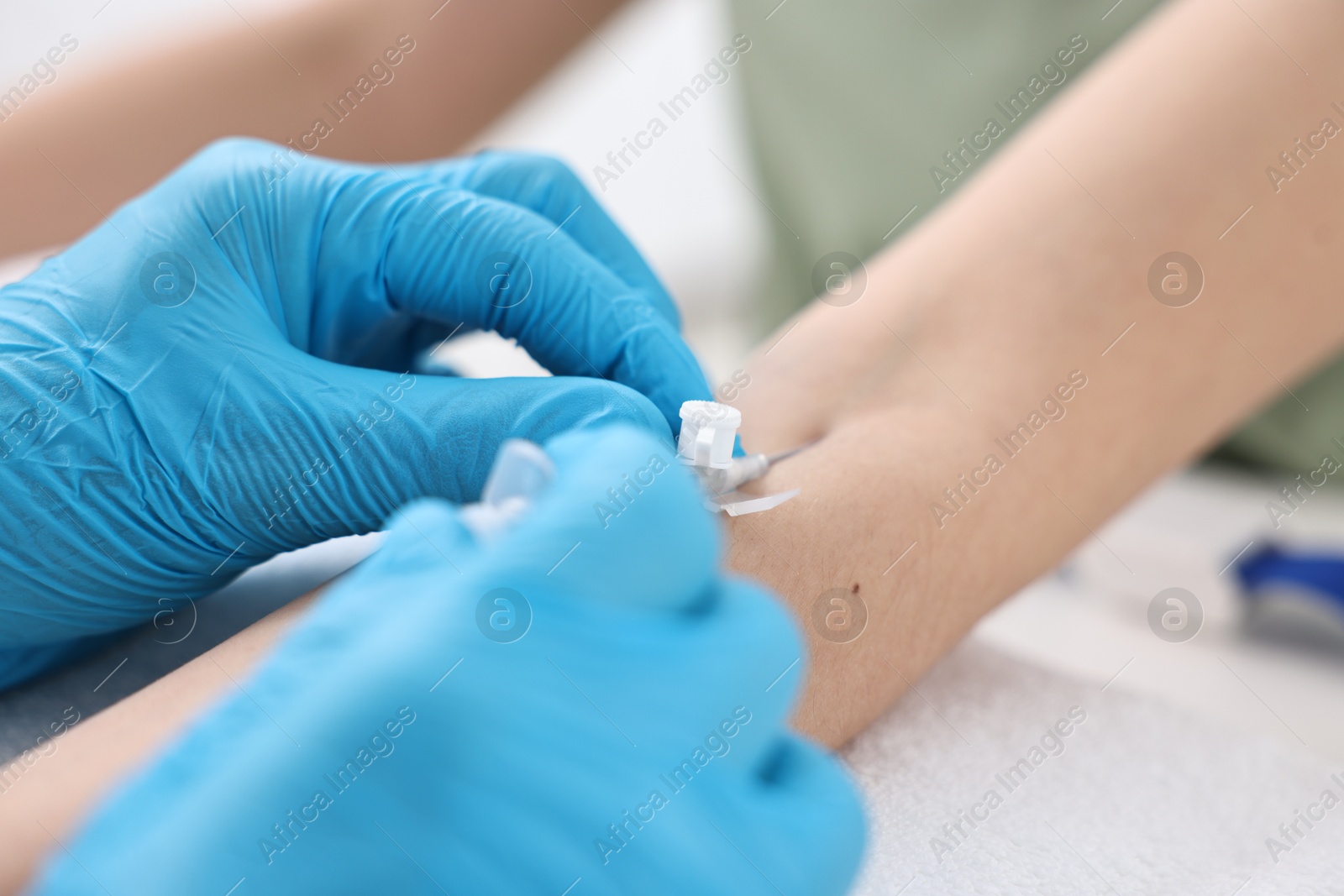 Photo of Nurse inputting catheter for IV drip in patient hand, closeup