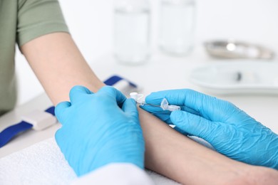 Photo of Nurse inputting catheter for IV drip in patient hand, closeup