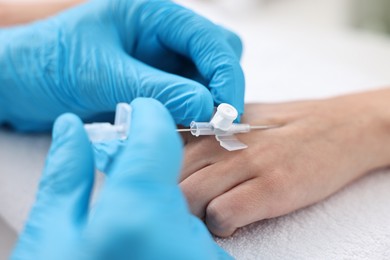 Photo of Nurse inputting catheter for IV drip in patient hand, closeup