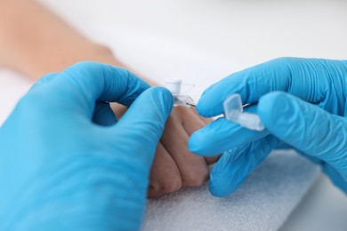 Photo of Nurse inputting catheter for IV drip in patient hand, closeup