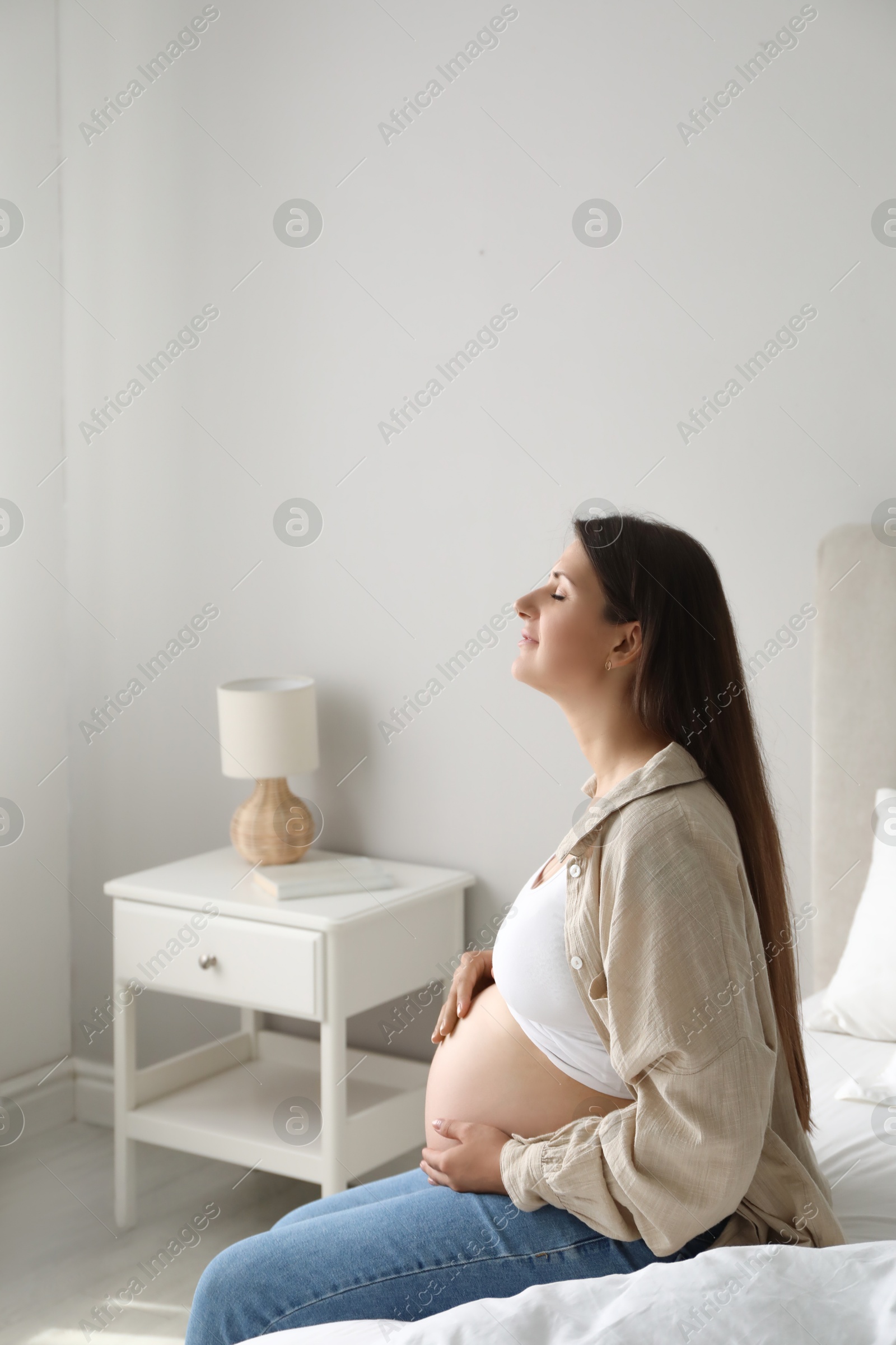 Photo of Beautiful pregnant woman on bed at home