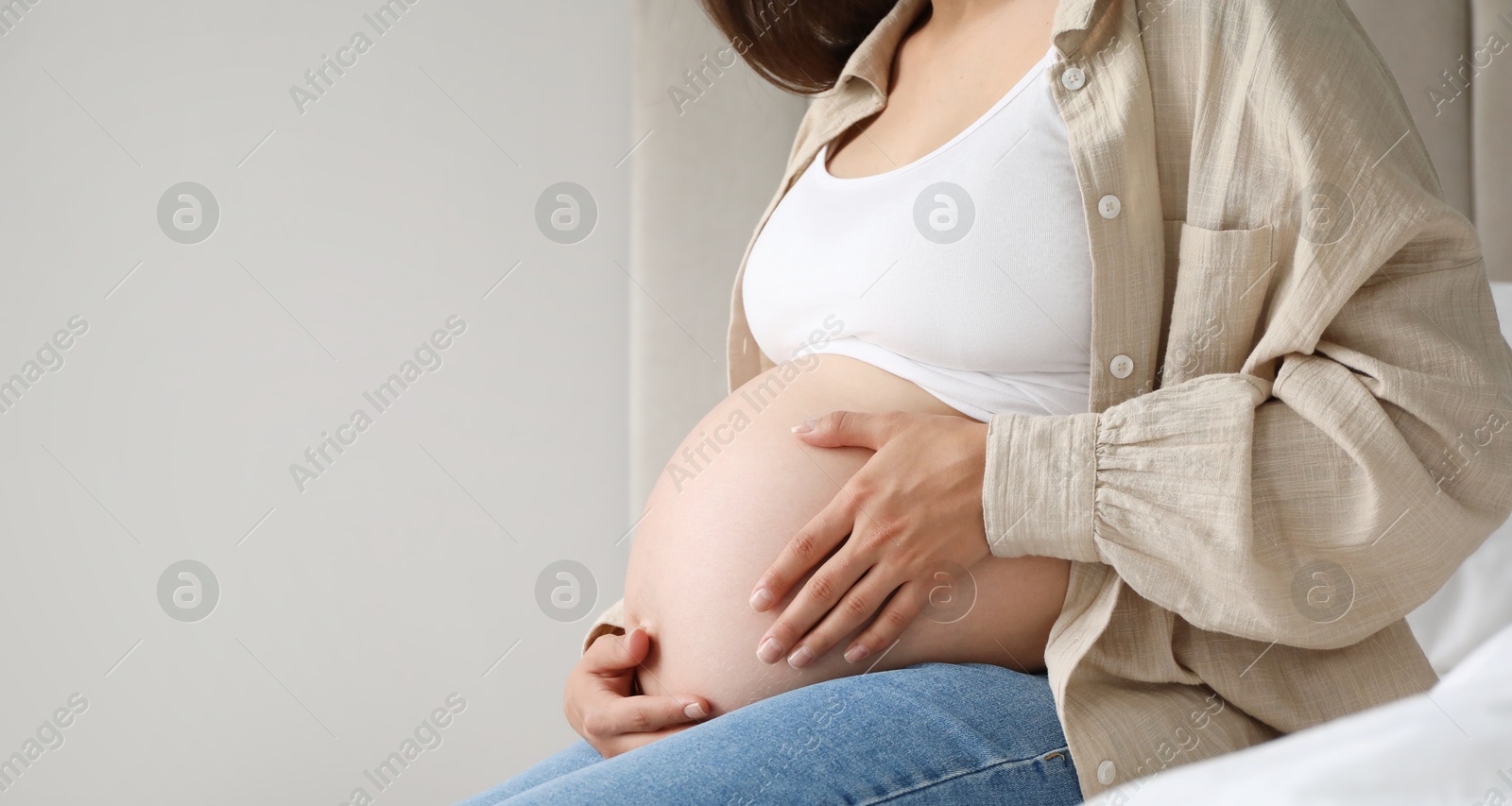 Photo of Pregnant woman on bed at home, closeup. Space for text