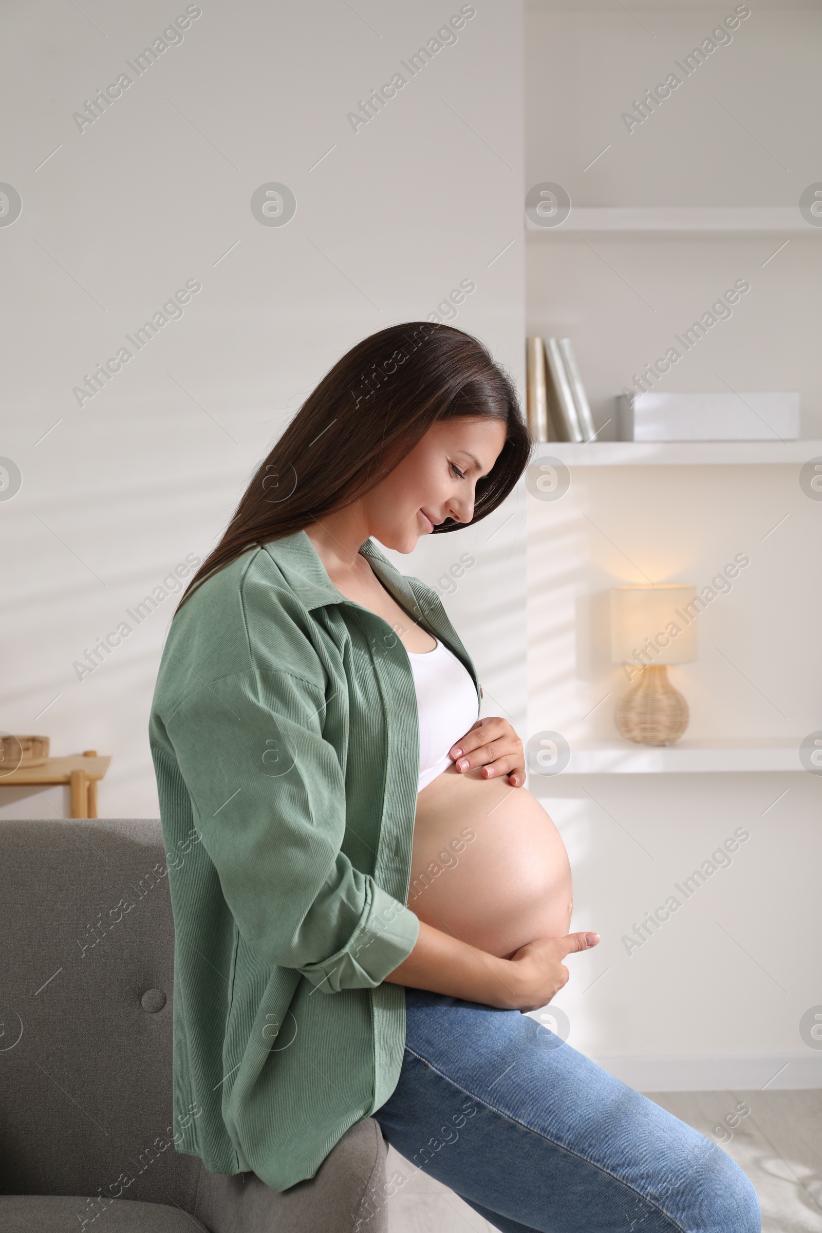 Photo of Beautiful pregnant woman sitting on sofa at home