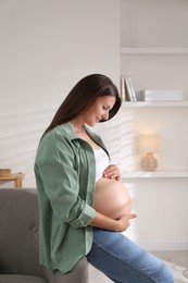 Photo of Beautiful pregnant woman sitting on sofa at home