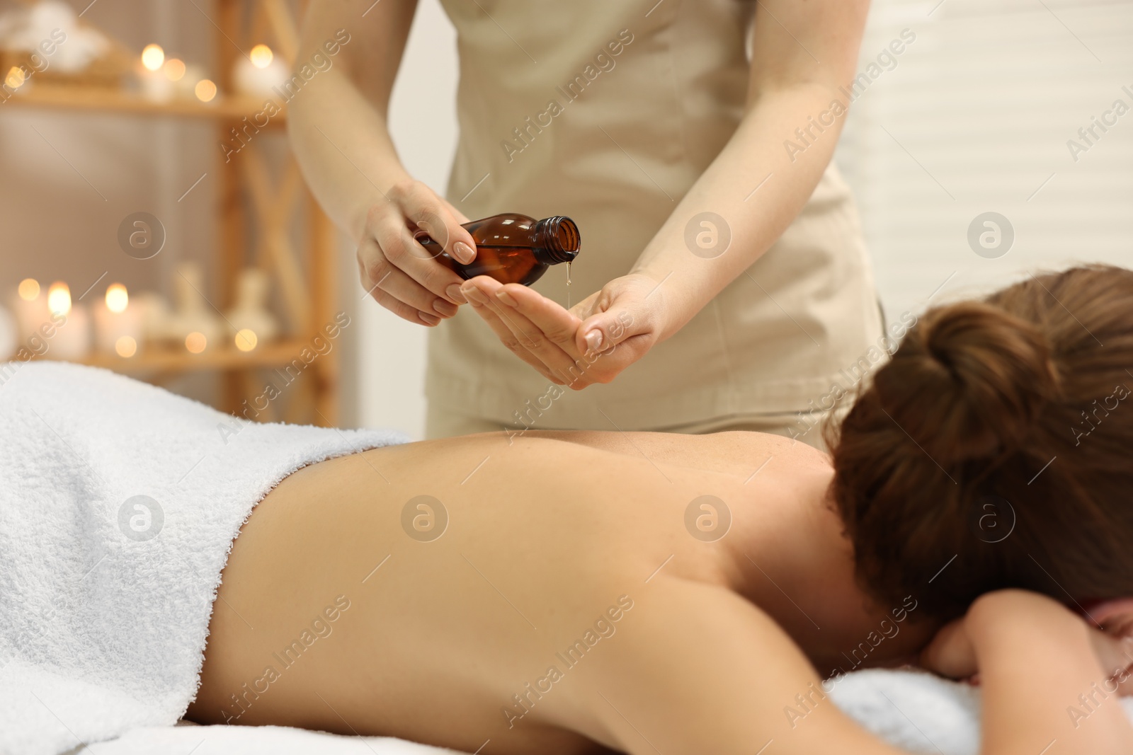 Photo of Aromatherapy. Woman receiving back massage with oil in spa salon, closeup