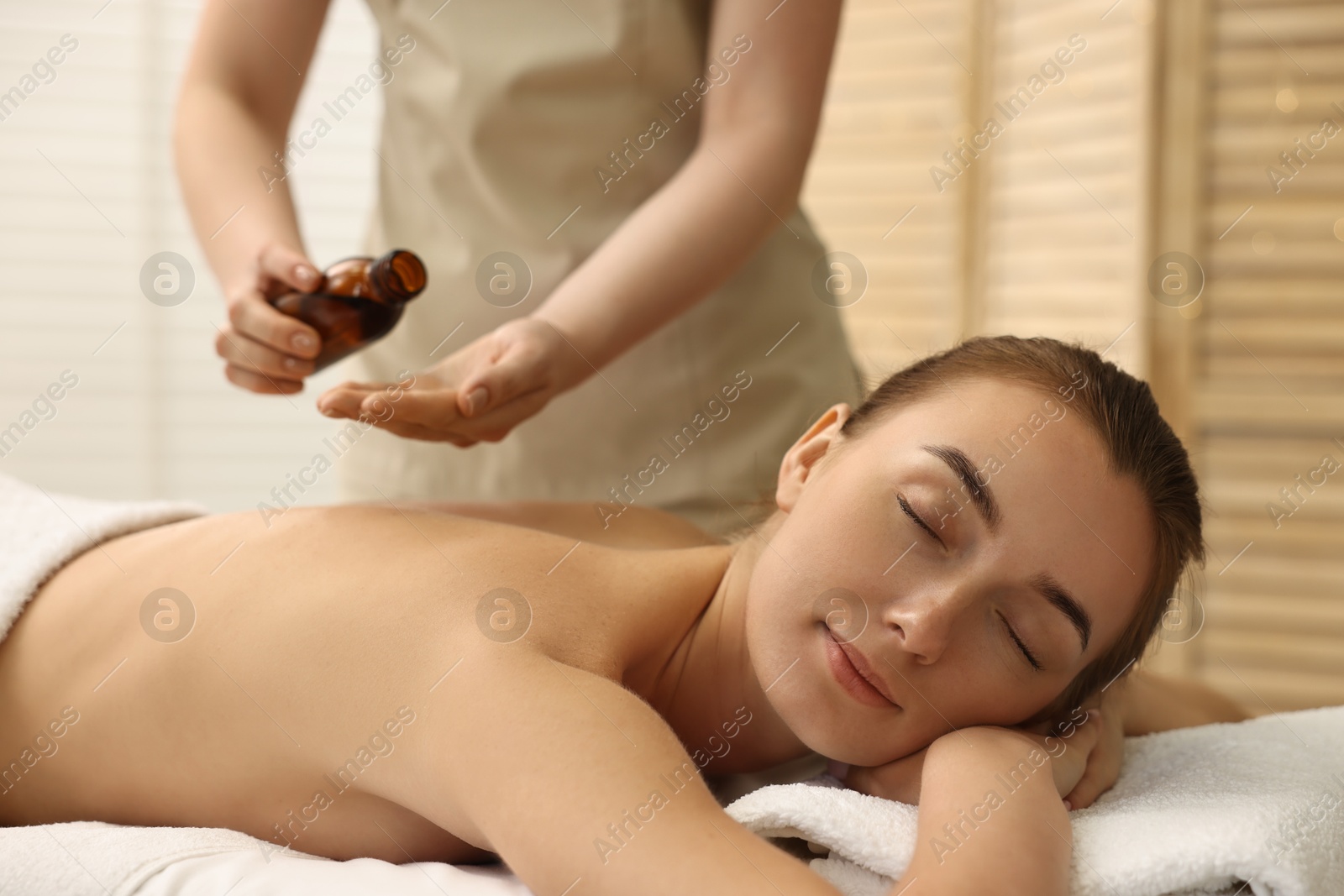 Photo of Aromatherapy. Beautiful woman receiving back massage with oil in spa salon