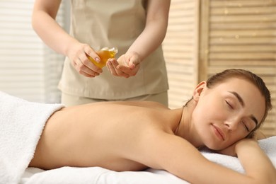 Photo of Aromatherapy. Beautiful woman receiving back massage with oil in spa salon