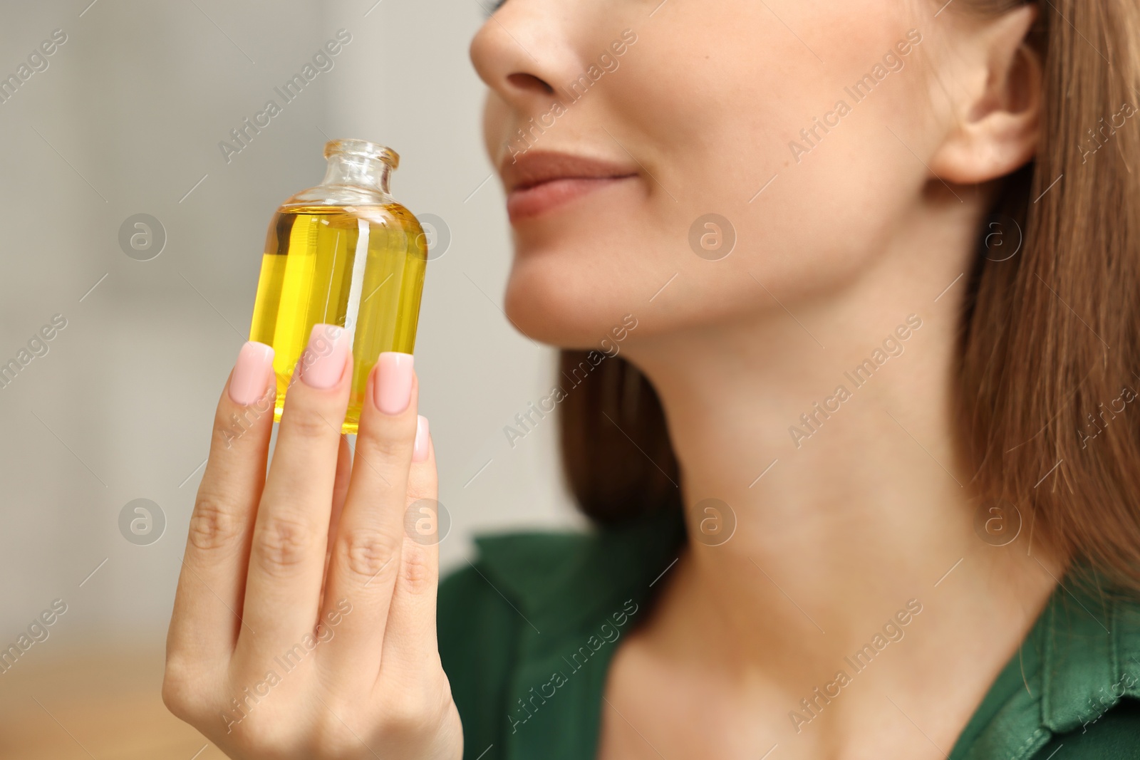 Photo of Aromatherapy. Woman with bottle of essential oil on light background, closeup