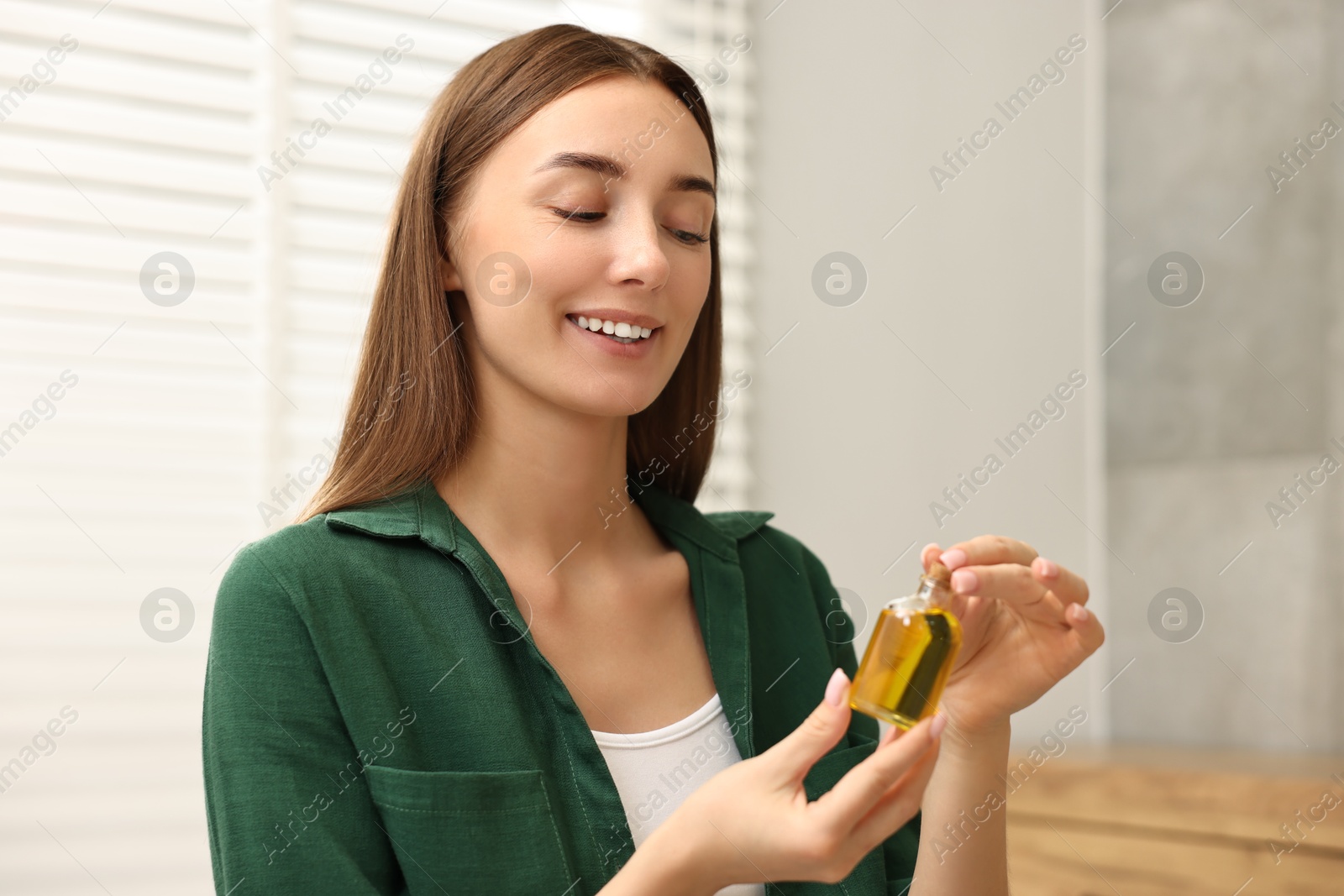 Photo of Aromatherapy. Beautiful woman with bottle of essential indoors