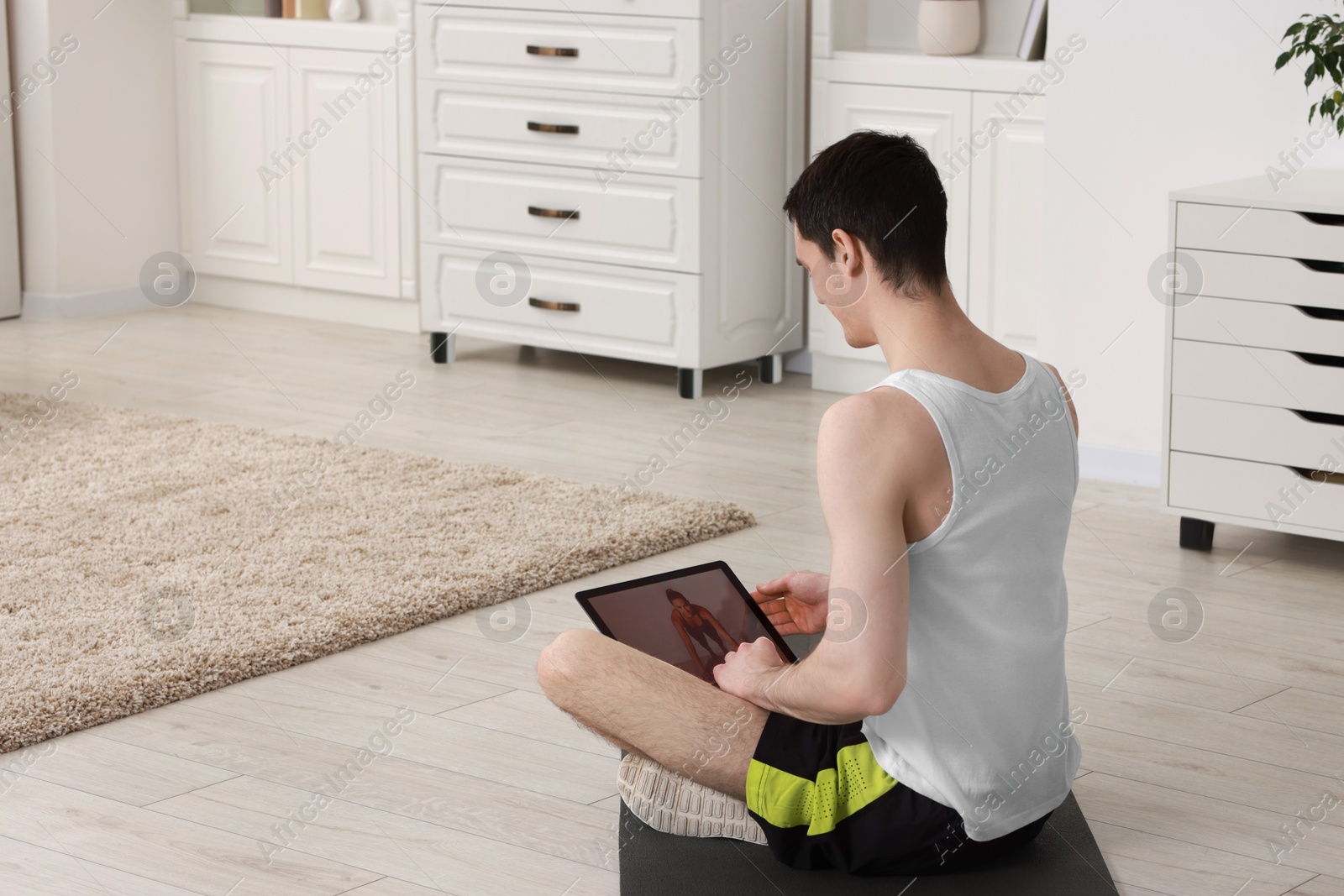 Photo of Online fitness trainer. Man watching tutorial on laptop indoors