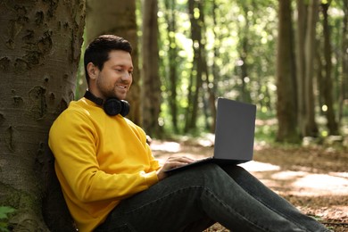 Smiling traveler working with laptop outdoors. Remote job