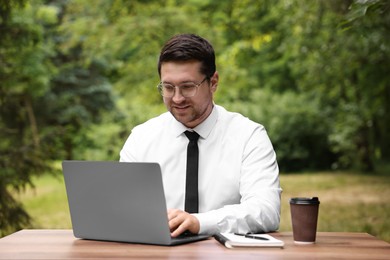 Photo of Businessman working with laptop at table outdoors. Remote job