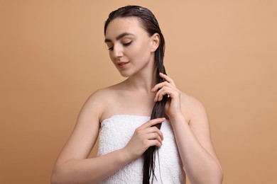 Photo of Beautiful woman applying hair mask on beige background