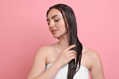 Photo of Beautiful woman applying hair mask on pink background